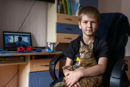 Nine-year-old Andrii holds his cat in his bedroom in Kherson, Ukraine.