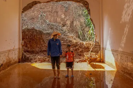 A mother and son stand inside their flooded home in Lao Cai province, Vietnam after Super Typhoon Yagi.