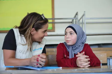 On Sept. 24, 2024, a UNICEF staff member speaks with Mariam, 10, displaced by violence and staying with her family in Amiliye public school, now being used as an IDP shelter, in Beirut, Lebanon.
