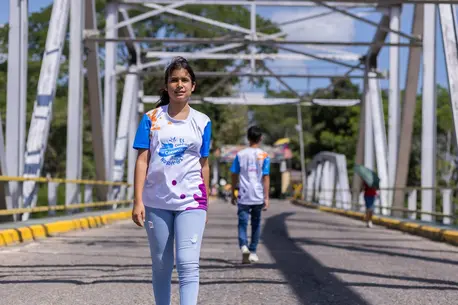 Wearing a UNICEF shirt, Aime, a 14-year-old migrant from Venezuela, crosses a bridge in Colombia.
