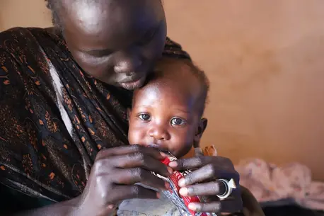 In Renk, Upper Nile State, South Sudan, mother feeds her child from a packet of ready-to-use therapeutic food (RUTF) supplied by UNICEF to treat malnourished children.