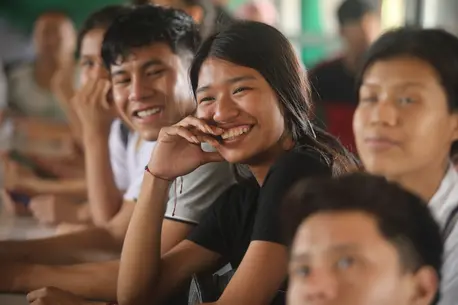 A smiling adolescent girl sits among other students at a UNICEF-supported school in Bolivia.