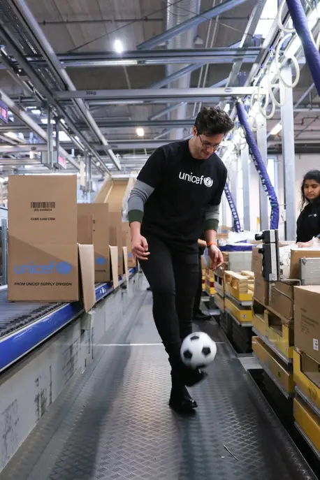 UNICEF Ambassador Doctor Mike takes a break from packing recreational kits at UNICEF's supply warehouse, kicking a soccer ball around.