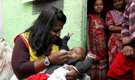 Minda Dentler, a Rotary ambassador, administers the polio vaccine to a child during a national immunization campaign in India.