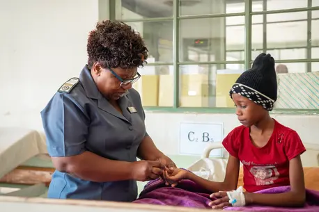 Female nurse touching young girl's finger for blood test