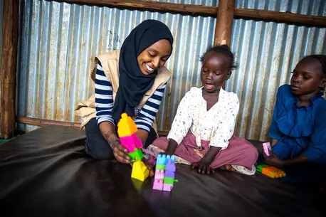 Social worker playing with Sudanese child refugees at a UNICEF-supported camp in Ethiopia.