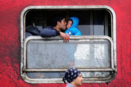 A father kisses his baby boy inside a train filled with refugees from Syria and Iraq travelling across Macedonia to the Serbian border, where they will continue their journey.