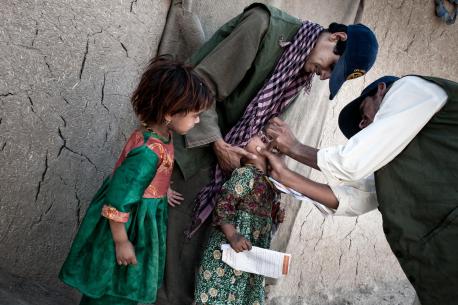 A vaccination worker administers a dose of oral polio vaccine to a girl Kandahar (July 2013). 