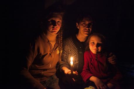 A woman and her daughters sit in candlelight in a bomb shelter on the outskirts of the city of Debaltsevo, Ukraine – where fighting has continued despite the ceasefire agreement.
