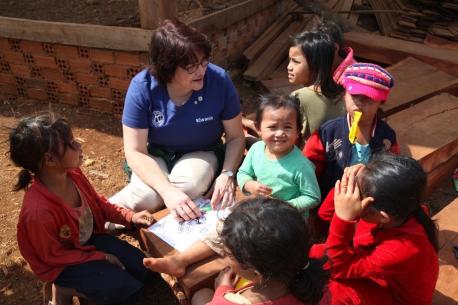 Kiwanis International President Sue Petrisin teaches children to draw on a field visit in Cambodia.
