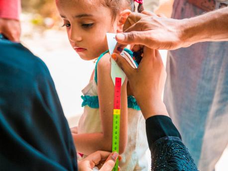 A child has her upper arm measured to screen for malnutrition as part of a door-to-door immunization campaign in Yemen in October 2017.