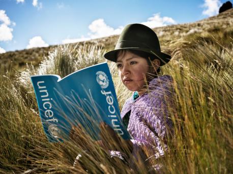 Girl Reading UNICEF Book in Field