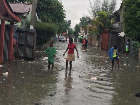 On 7 September 2017 in Haiti, children and women wade through a street in Hinche as Hurricane Irma approaches.
