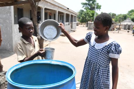 Two young children drinking safe water in the village of Kotouba, in northwest Côte d'Ivoire.