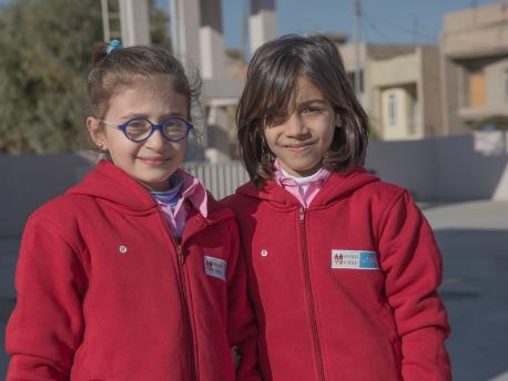 Arah (right) and Saba (left), Syrian refugees living in the Kurdistan Region of Iraq, wear their new winter uniforms at Rubar School in Erbil. 