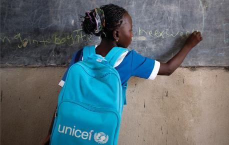 Girl with a UNICEF Backpack Writing on Blackboard