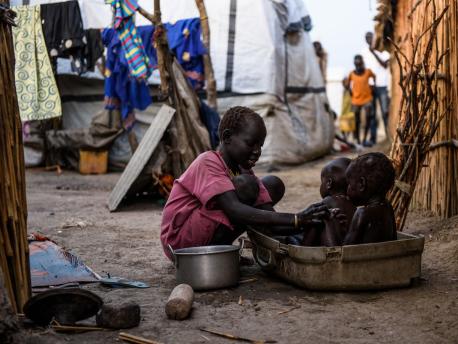 A young girl washes her siblings in the shell of a damaged suitcase in the Protection of Civilians (PoC) site in Bentiu, South Sudan, May 2017.