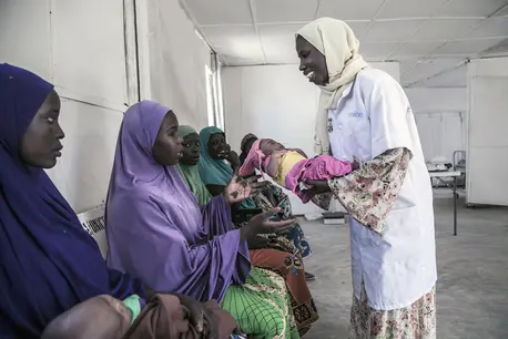 A health worker returns baby Aishat to her mother Hausa at a UNICEF-supported health clinic in the Muna Garage displacement camp, Maiduguri, Borno State, northeast Nigeria. A health worker returns baby Aishat to her mother Hausa at a UNICEF-supported health clinic in the Muna Garage displacement camp, Maiduguri, Borno State, northeast Nigeria.