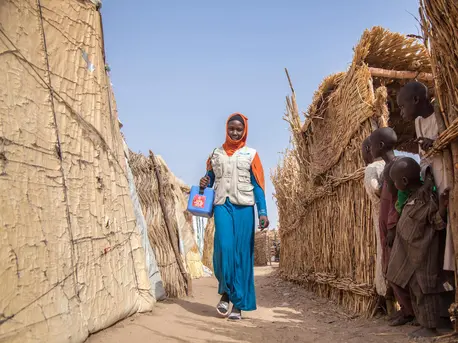 Aisha, a UNICEF-supported polio team vaccinator, walks through Muna Garage IDP camp in Maiduguri, Borno State, northeast Nigeria in January 2018.