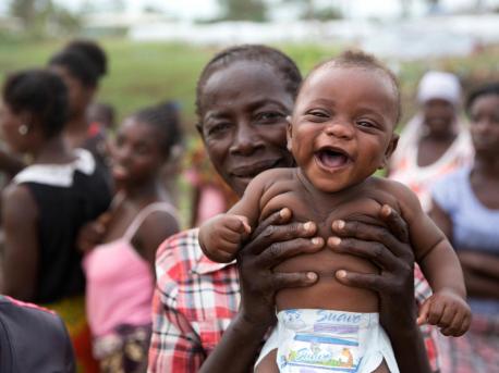 Baby Francisco smiles as people displaced by Cyclone Idai celebrate the arrival of food packages at a UNICEF-supported relief center in Beira, Mozambique on April 18, 2019.