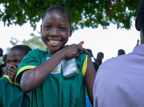 A happy girl prepares for her immunization against measles, mumps, rubella and polio during a nationwide campaign run by the Ugandan Government with support from UNICEF and WHO.