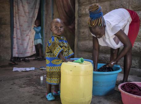 On 3 October 2020 in Kenya, Cinderella Akinyi Othiambo, 22, washes clothes as her one-and-a-half-year-old nephew, Duncan Makoa, looks to the camera, outside her home in Mathare, an informal settlement in Nairobi.