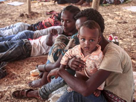 An Ethiopian refugee who fled fighting in Tigray province sits holding a child in a hut at the Um Raquba camp in Sudan's eastern Gedaref province, on 16 November 2020.