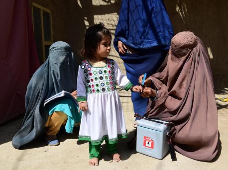 In Afghanistan's Kandahar Province on March 8, 2020, a UNICEF-supported polio vaccinator marks a girl's finger to indicate she has received the vaccine.