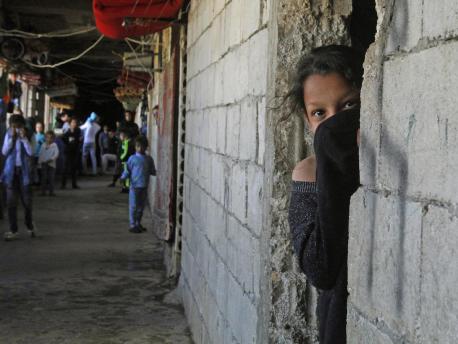 On March 17, 2020, a Syrian refugee, her face covered to protect against COVID-19, looks out from a doorway in an unfinished building where she has been living in the city of Sidon in southern Lebanon. 