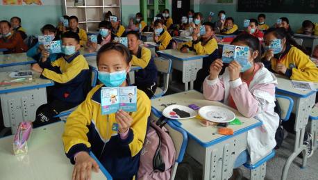 Students at a school in Datong County, Qinghai Province, China, hold up health education leaflets developed by UNICEF as part of the response to COVID-19. 
