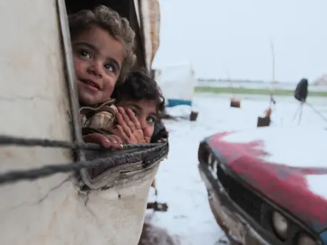 On 12 February 2020, children peer out from a tent at a recently established informal settlement which continues to receive newly displaced families from southern Idlib and rural Aleppo governorates in northwest Syrian Arab Republic. On 12 February 2020, children peer out from a tent at a recently established informal settlement which continues to receive newly displaced families from southern Idlib and rural Aleppo governorates in northwest Syrian Arab Republic.