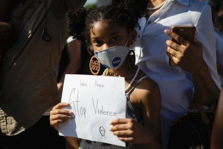 A young black girl holds a simple but powerful poster as she protests against racialized violence 