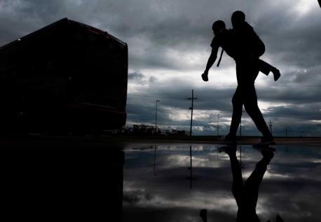 A man carries a child on his back as he walks to board a bus for evacuation before the arrival of Hurricane Laura in Lake Charles, Louisiana on August 25, 2020. 