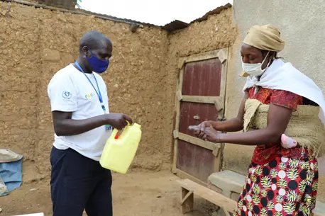 Man with a Container Helps Woman Wash Hands