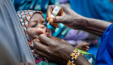 A volunteer community mobilizer administers the oral polio vaccine to a child in Fanisau Ugongo Village, Kano State, Nigeria.