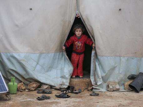 On 19 January 2021, a child looks out a tent in Kafr Losin Camp in northwest Syrian Arab Republic. UNICEF is working with partners to provide displaced children in Syria with the supplies and services they need to survive and thrive. 