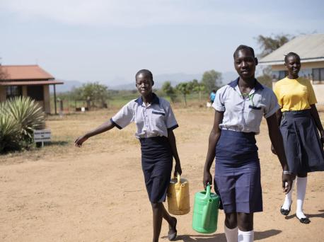 From left: 17-year-olds Margaret and Elizabeth, and Nite, 19, carry water from the newly rehabilitated borehole at Ilumum Primary School in Torit, South Sudan. 
