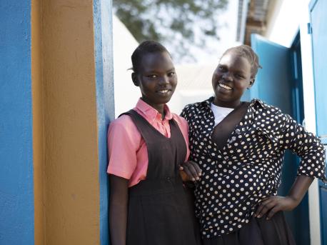 On February 3, 2021, Keziah, 14, (left) and Elizah, 16, stand in front of the newly rehabilitated latrine at AIC Nursery and primary school in Torit, South Sudan..