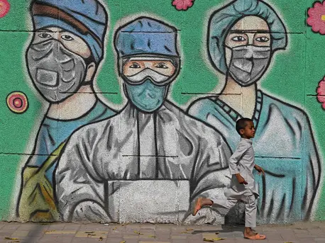On March 21, 2021 in India, a child runs past a mural depicting frontline health care workers, along a road in New Delhi. On March 21, 2021 in India, a child runs past a mural depicting frontline health care workers, along a road in New Delhi.