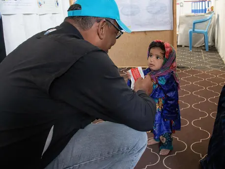 UNICEF Representative in Afghanistan Hervé Ludovic De Lys greets a girl enjoying a packet of Ready-to-Use Therapeutic Food at a clinic in the Sabz-e-Shark IDP camp in Herat on September 29, 2021. UNICEF Representative in Afghanistan Hervé Ludovic De Lys greets a girl enjoying a packet of Ready-to-Use Therapeutic Food at a clinic in the Sabz-e-Shark IDP camp in Herat on September 29, 2021.