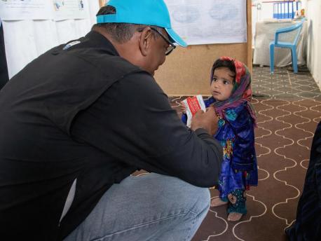 UNICEF Representative in Afghanistan Hervé Ludovic De Lys greets a girl enjoying a packet of Ready-to-Use Therapeutic Food at a clinic in the Sabz-e-Shark IDP camp in Herat on September 29, 2021.