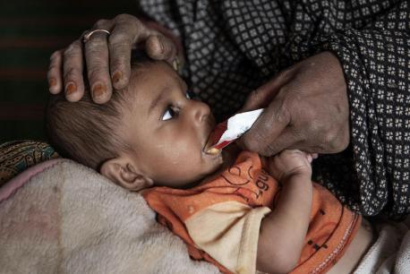 In Maywand, Afghanistan, a 9-month-old boy suffering from severe acute malnutrition is given a packet of Ready-to-Use Therapeutic Food (RUTF) provided by a UNICEF-supported mobile health and nutrition team.