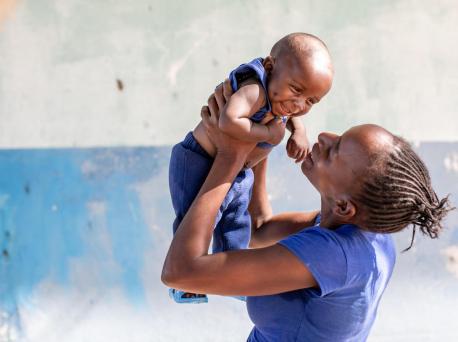 On January 27, 2020, 6-month-old Misheck is held aloft by his mother outside the UNICEF-supported Luumbo Health Center in Zambia.