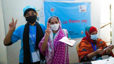 A UNICEF volunteer celebrates with fellow community member Belaton, 53, who has just received her COVID-19 vaccination at Shimantik Clinic, Khilgaon, Dhaka, Bangladesh, on Oct. 10, 2021.