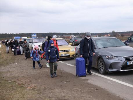 On February 27, 2022, as military operations continue in Ukraine, people scrambling to get their children out of harm's way walk alongside vehicles lined up to cross the border into Poland. 