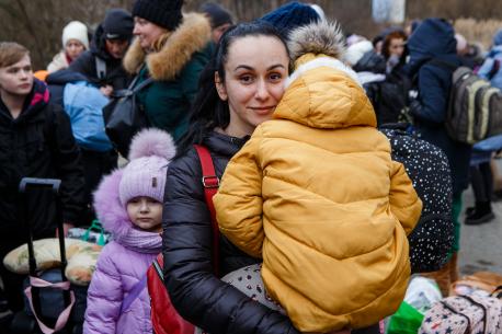A mother fleeing Ukraine with her family holds one of her children as they wait to cross the border into Slovakia in March 2022.