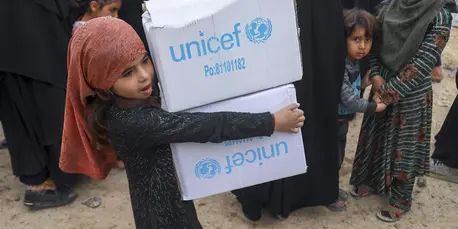 Displaced Syrian children help their parents distribute winter clothes from UNICEF at the Al-Hol camp in Hasakah, northeast Syria, on March 2, 2022.
