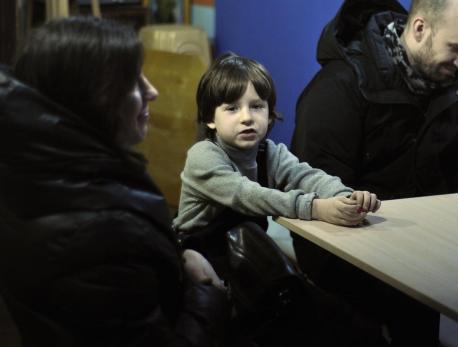 Davyd, 7, sits with his mother and uncle at a temporary shelter in a Kyiv church in March 2022. 