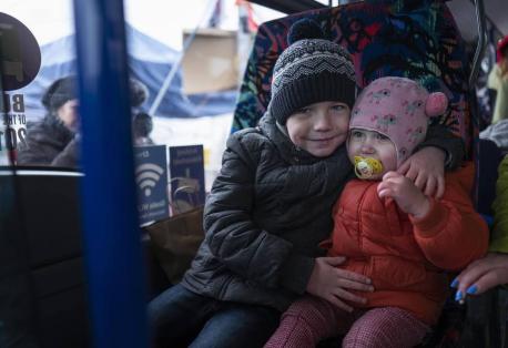 On April 2, 2022, in Poland, 6-year-old Artur embraces 2-year-old sister Anna on a shuttle bus from Medyka to Przemysl after crossing the border from Ukraine with their mother, Oksana to escape the constant bombardment of their home city of Sumy.