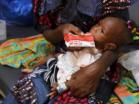Konata Karko, a 24-year-old mother of two, feeds her acutely malnourished 1-year-old daughter, Mariam, with Ready-to-Use Therapeutic Food at the UNICEF-supported Health Center in Bobo-Dioulasso, southwestern Burkina Faso on May 12, 2022. 